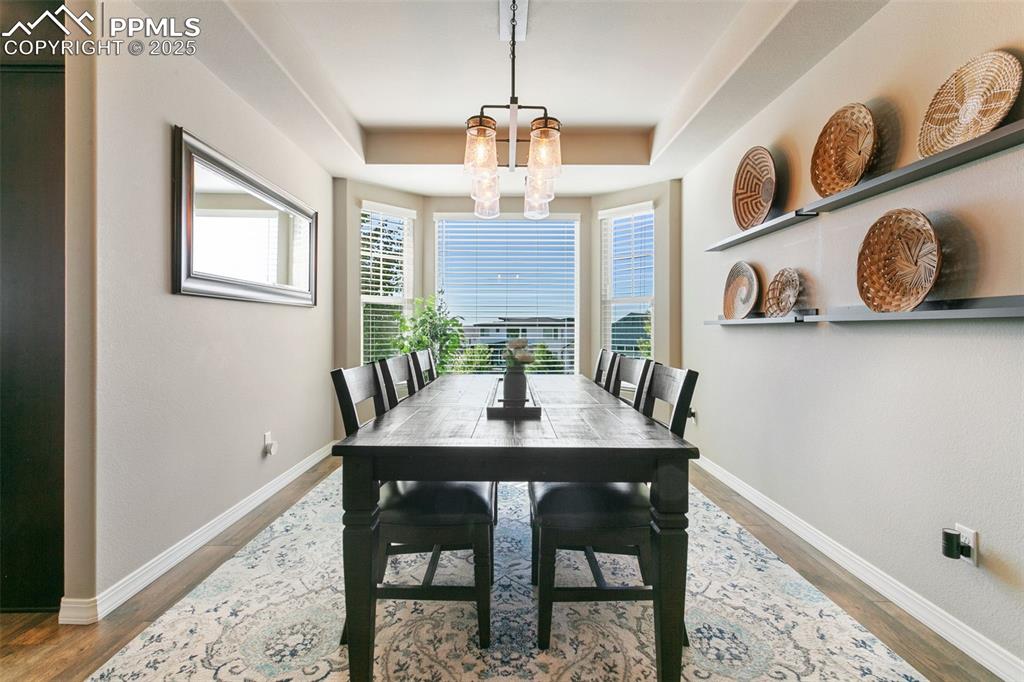 Image 11 of 50: Dining room featuring light wood-style floors, a tray ceiling, and a chande