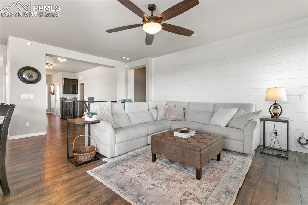Image 13 of 50: Living room with dark wood-type flooring and ceiling fan