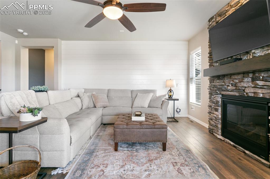 Image 15 of 50: Living room with wood finished floors, a fireplace, ceiling fan, and wooden