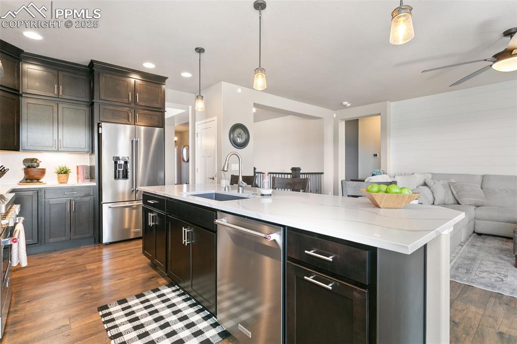 Image 20 of 50: Kitchen with open floor plan, stainless steel appliances, hanging light fix