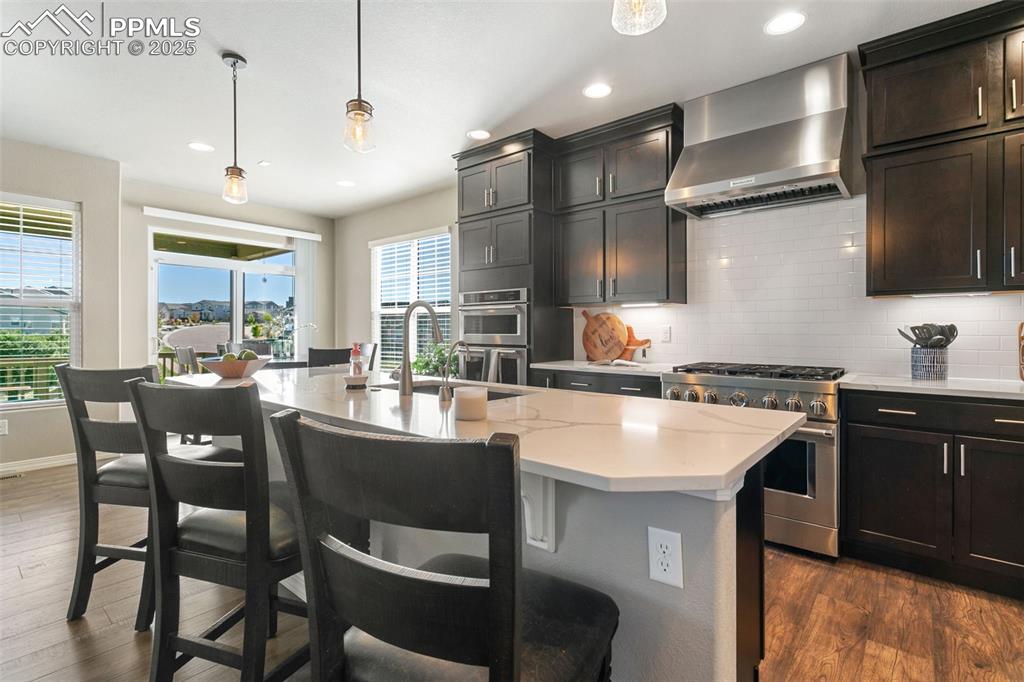 Image 23 of 50: Kitchen with pendant lighting, decorative backsplash, wall chimney exhaust 