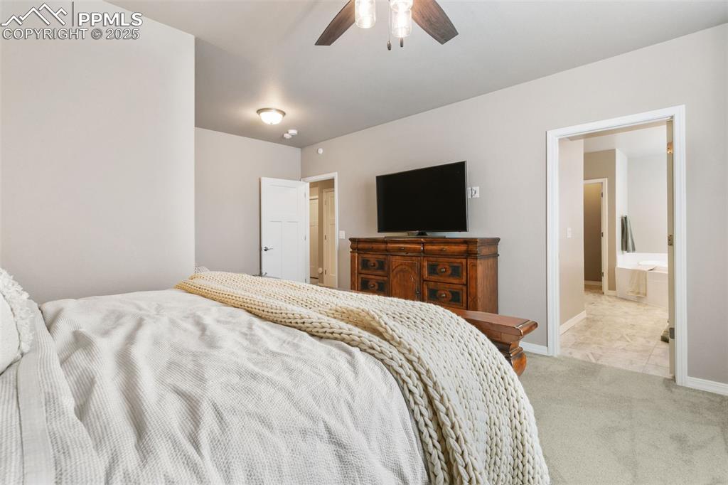 Image 29 of 50: Carpeted bedroom featuring a ceiling fan, ensuite bathroom, and tile patter