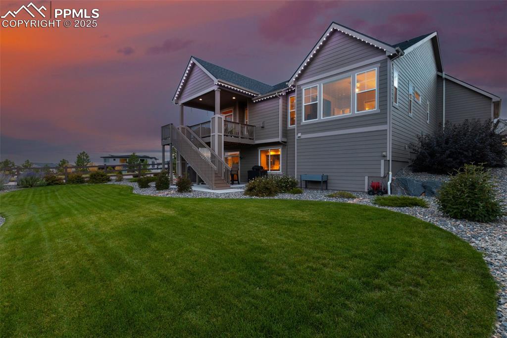 Image 4 of 50: Back of property at dusk featuring a patio, a lawn, stairs, and a deck