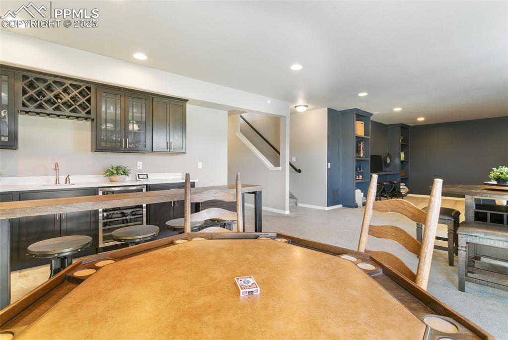 Image 45 of 50: Dining area with wet bar, recessed lighting, wine cooler, light colored car