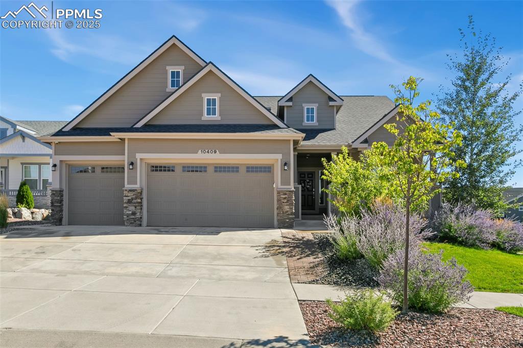Image 7 of 50: Craftsman house featuring a shingled roof, concrete driveway, and stone sid