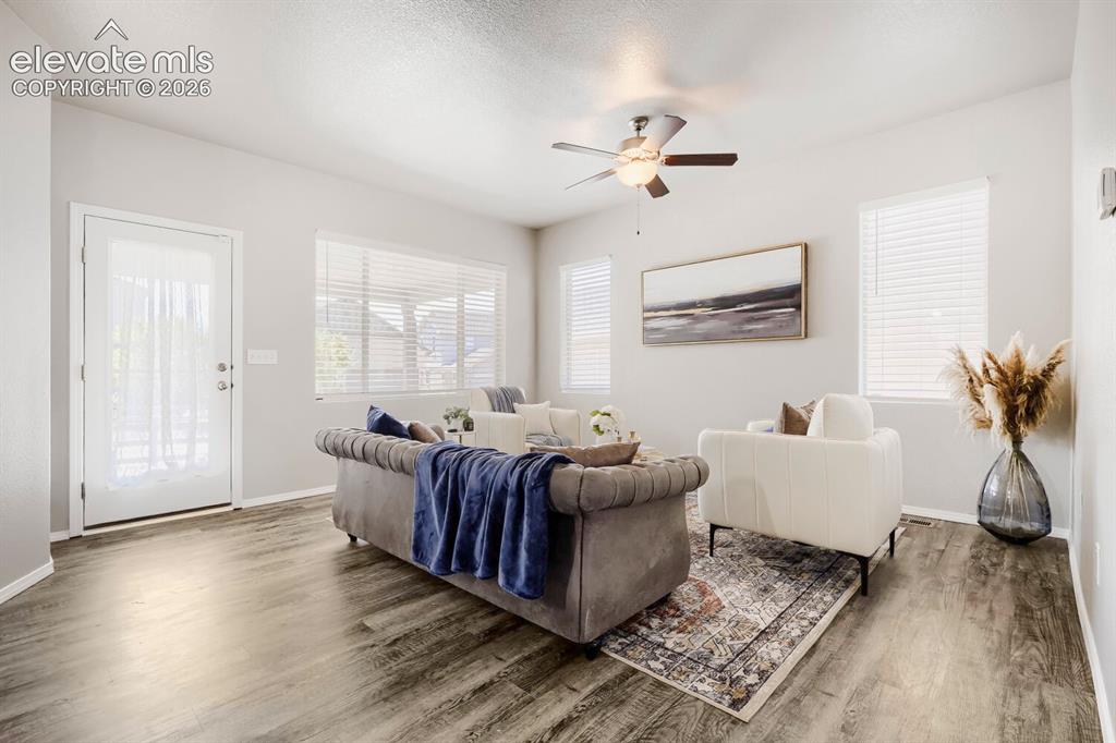 Image 11 of 35: Spacious living area featuring wood-finish flooring, light-toned walls, mul