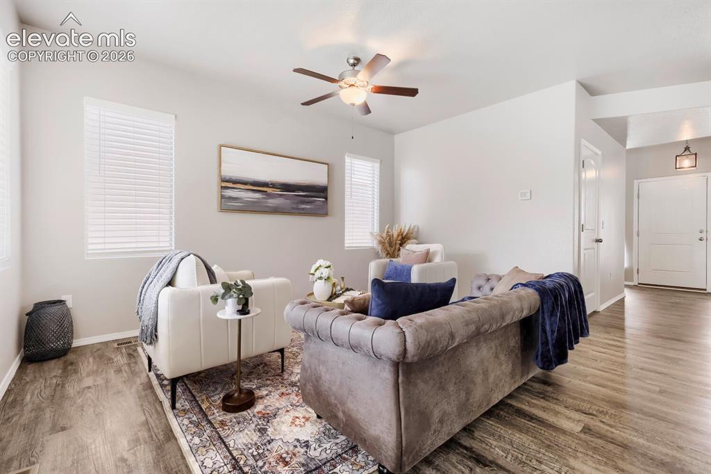Image 12 of 35: Bright living space featuring wood-finish flooring and a ceiling fan with i
