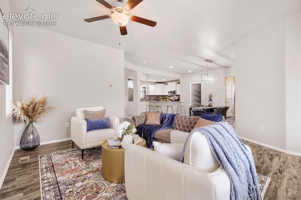 Image 13 of 35: Open-concept living space featuring wood-finish flooring, a ceiling fan wit