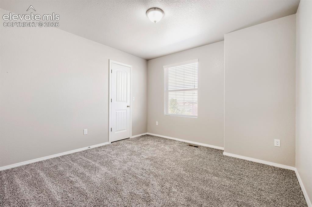 Image 15 of 35: Carpeted interior room featuring light gray walls, a single window with bli