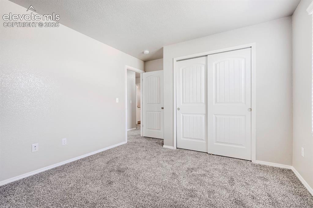 Image 19 of 35: Bedroom featuring neutral wall tones, gray plush carpeting, and white baseb