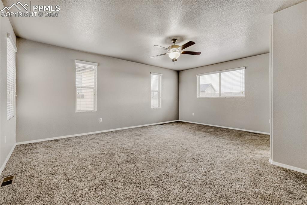 Image 20 of 34: Master bedroom with windows, carpet, ceiling fan, and ensuite bathroom