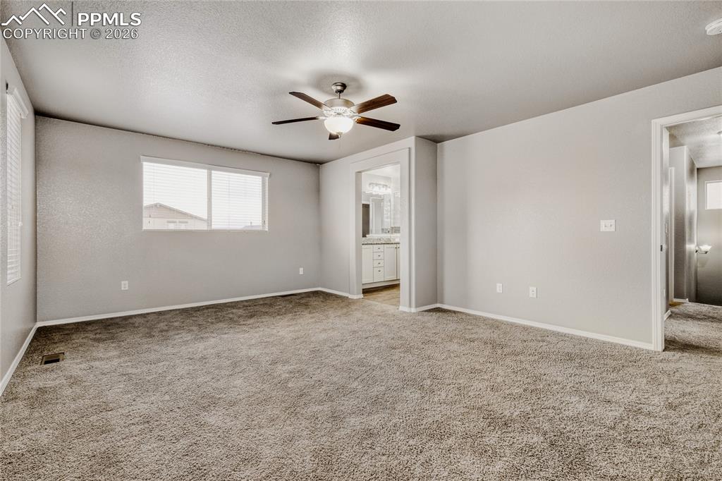 Image 21 of 34: Master bedroom with windows, carpet, ceiling fan, and ensuite bathroom