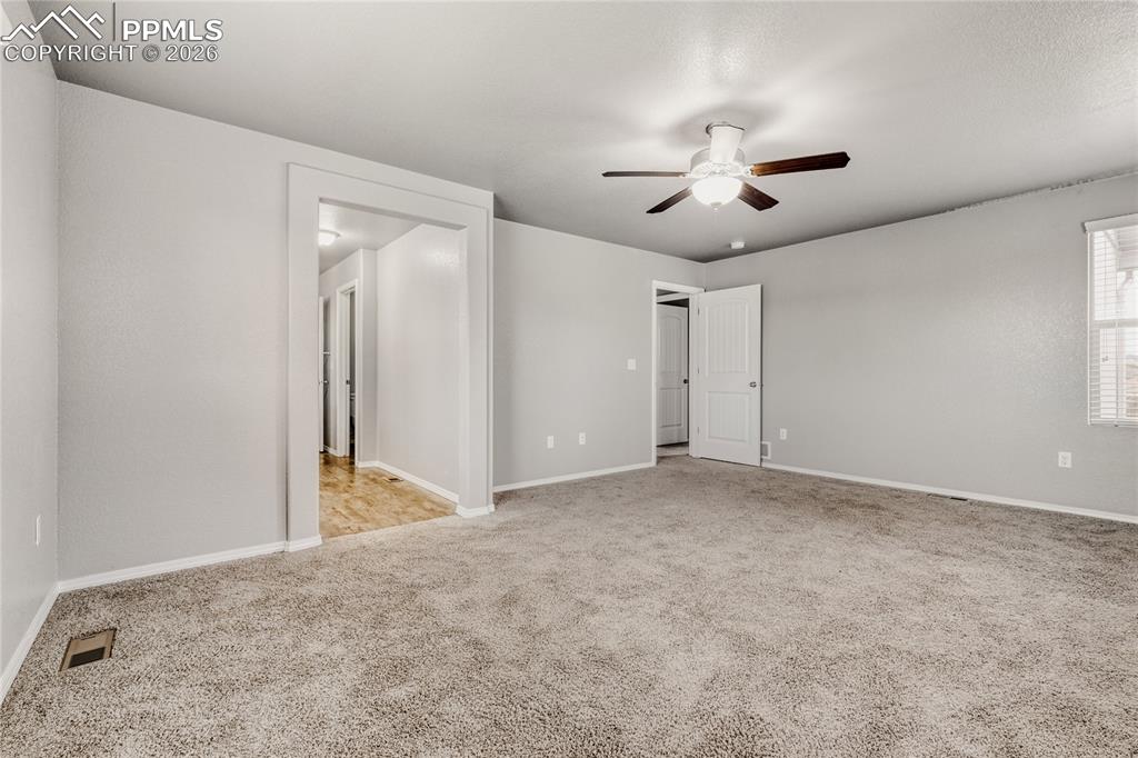 Image 22 of 34: Master bedroom with windows, carpet, ceiling fan, and ensuite bathroom