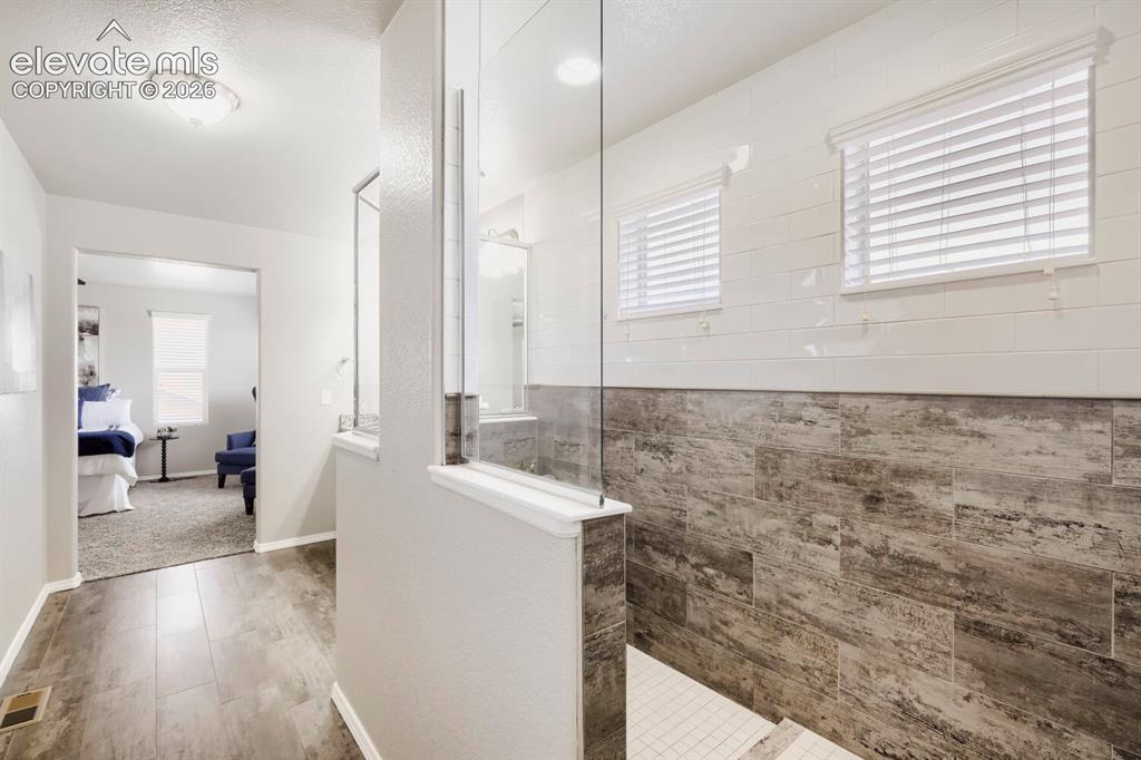 Image 23 of 35: Walk-in shower featuring glass enclosure, contrasting large-format wall til