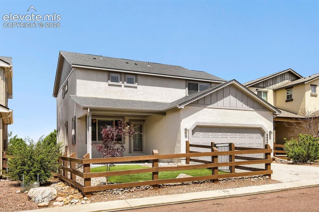 Image 27 of 35: Contemporary stucco exterior with a two-car garage, covered porch, fenced f