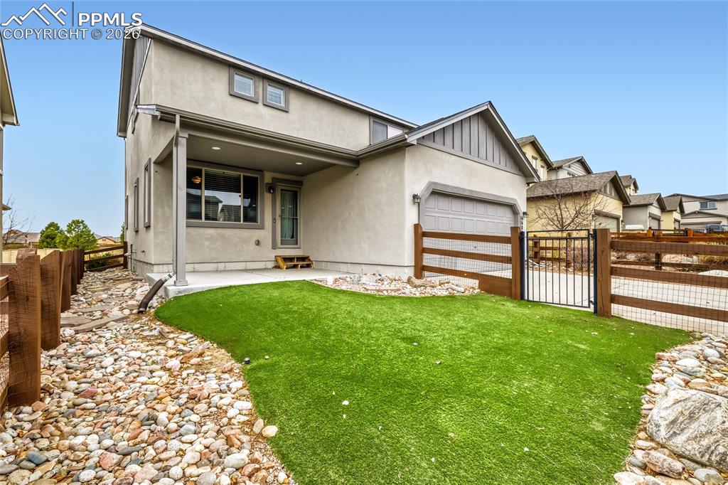 Image 28 of 34: View of back of house featuring a gate, a patio area, and attached garage