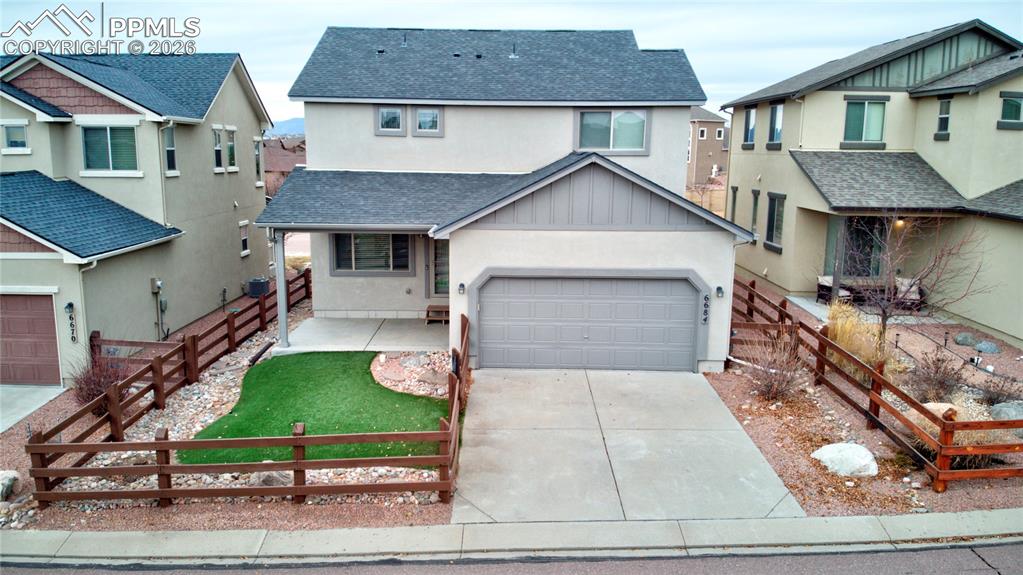 Image 29 of 34: View of front of home with  shingled roof concrete driveway, a garage, a re