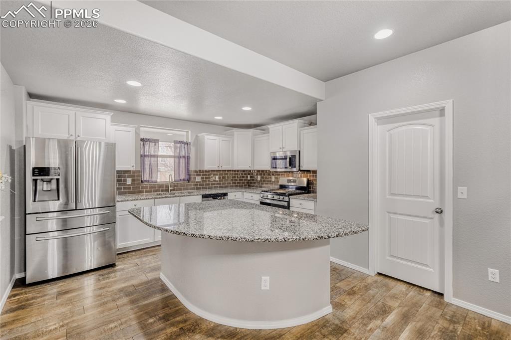 Image 7 of 34: Kitchen with stainless steel appliances, white cabinetry, tasteful backspla
