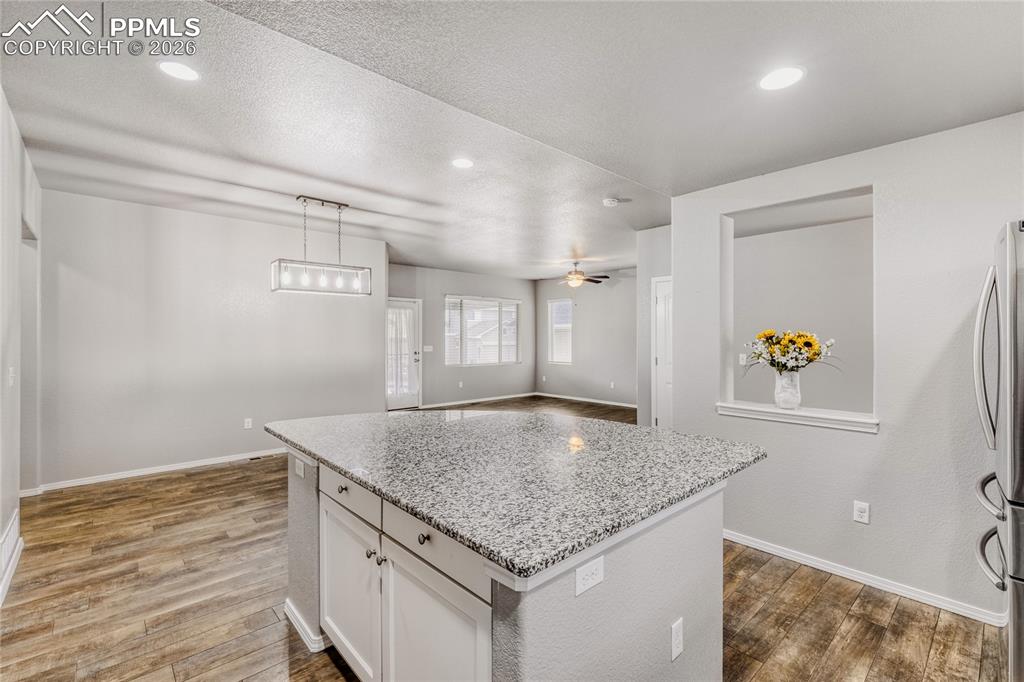 Image 9 of 34: Kitchen with LVP flooring, light granite counters, white cabinetry, a kitch