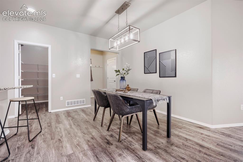 Image 9 of 35: Dining area featuring wood-finish flooring, light gray wall paint, and a mo