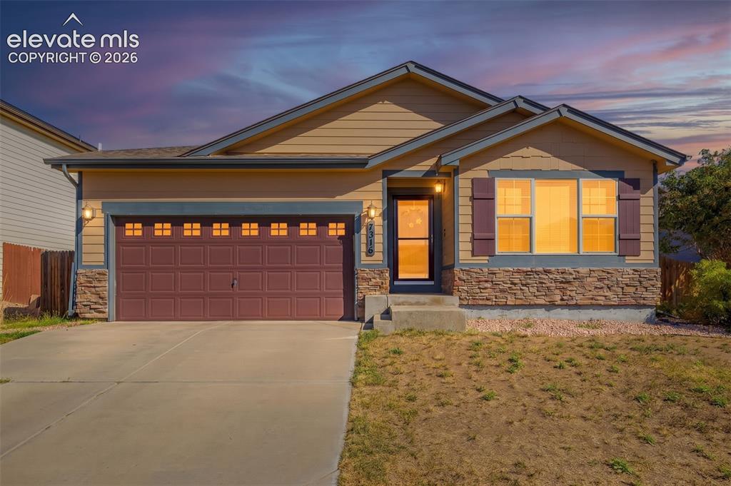 Caption: Single-story residence featuring a two-car garage with transom windows, a concrete driveway, and sto