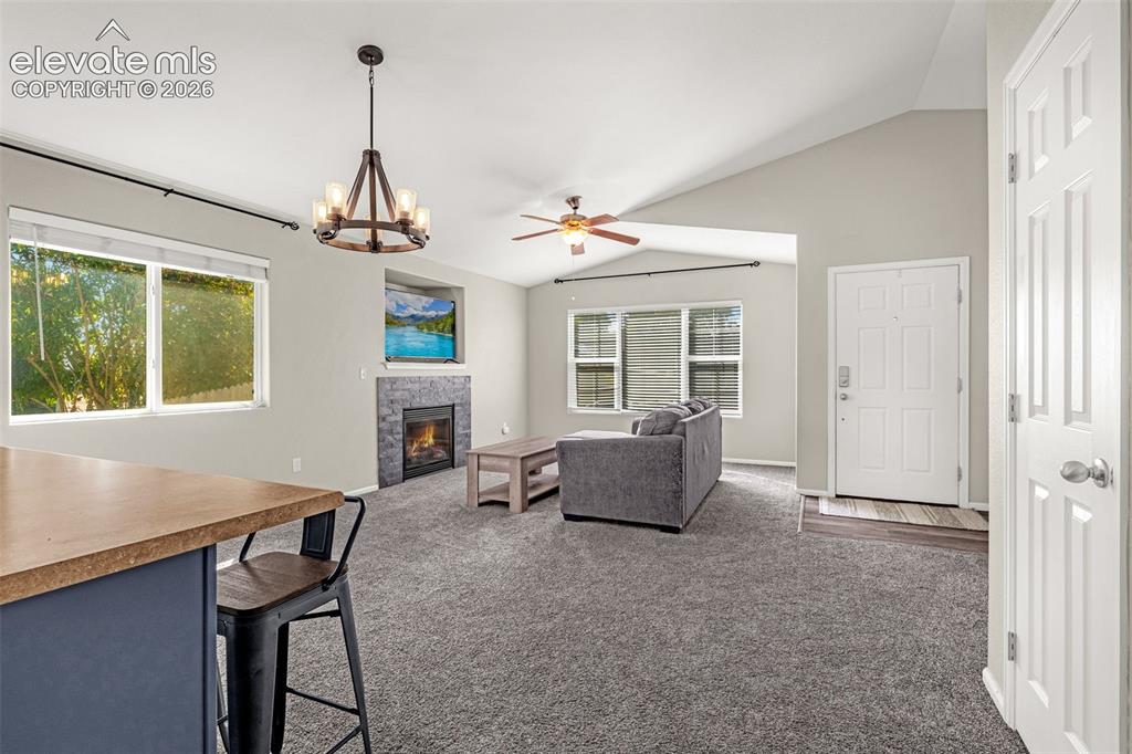 Image 12 of 37: Vaulted ceiling with an overhead fan, stone-clad fireplace, built-in displa