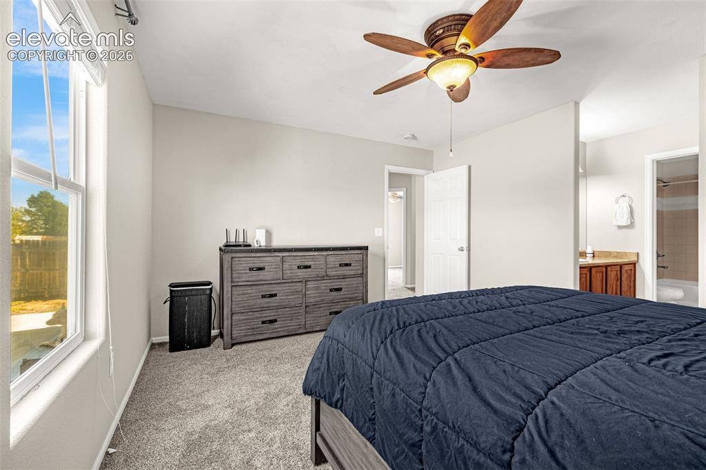 Image 18 of 37: Vaulted ceiling with a ceiling fan, carpeted flooring, and a large window