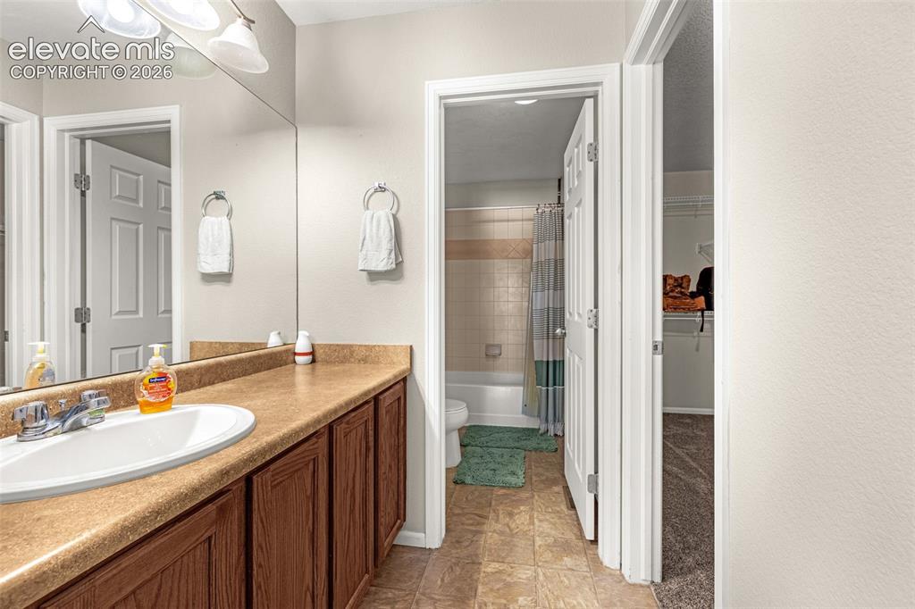 Image 19 of 37: Vanity with an integrated sink, wood-finish cabinetry, and a large mirror