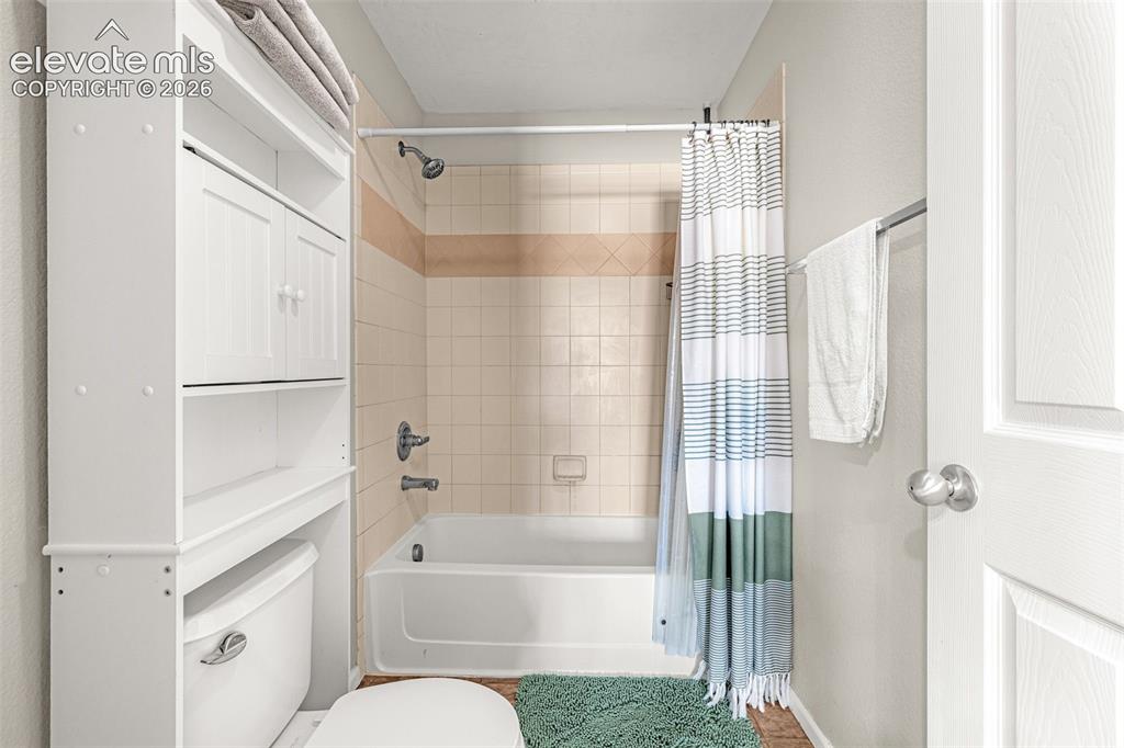 Image 20 of 37: Built-in over-toilet storage cabinetry, white paneled door, and a tiled sho