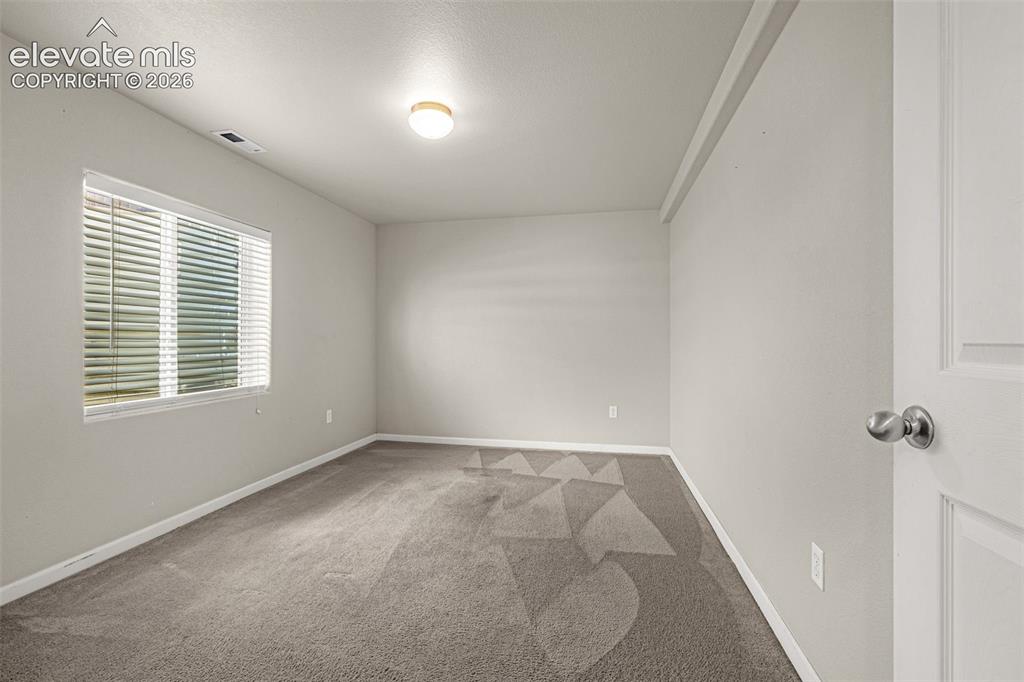 Image 26 of 37: Neutral tone walls, ceiling-mounted light fixture, and carpeted flooring