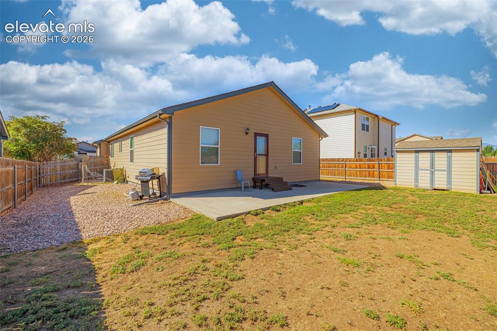 Image 28 of 37: Expansive backyard featuring a concrete patio, a detached storage shed, and