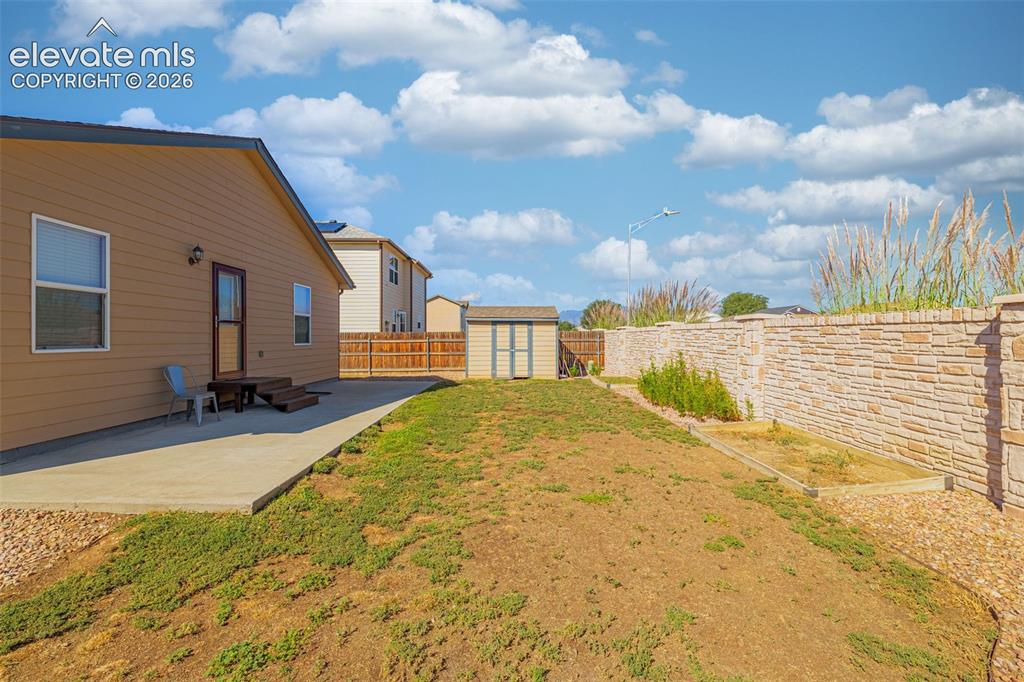 Image 29 of 37: Private backyard featuring a concrete patio, exterior access, a storage she