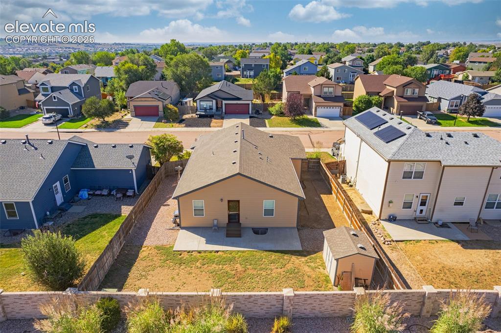 Image 31 of 37: Rear exterior with a concrete patio, wood fence, and an auxiliary storage s
