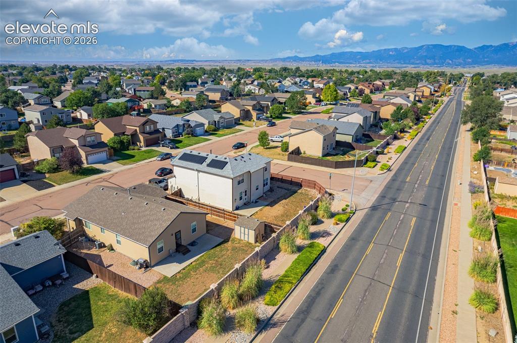 Image 32 of 37: Residential neighborhood with paved streets, mature trees, and distant moun