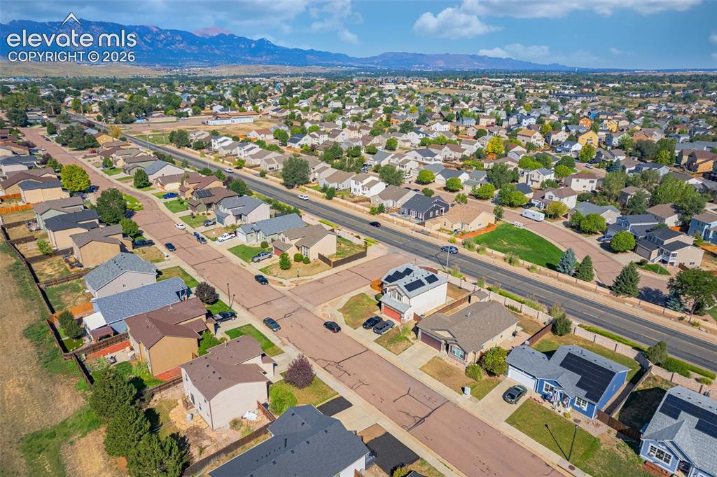 Image 34 of 37: Residential neighborhood featuring a paved street, mature trees, and mounta