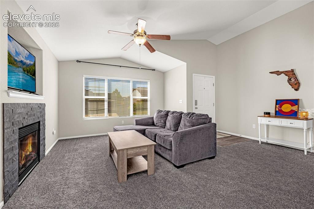 Image 5 of 37: Vaulted ceiling, ceiling fan, fireplace with stacked stone surround, multip