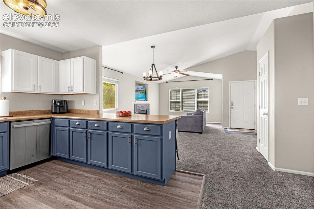 Image 9 of 37: Open-concept living area featuring vaulted ceilings, wood-finish flooring,