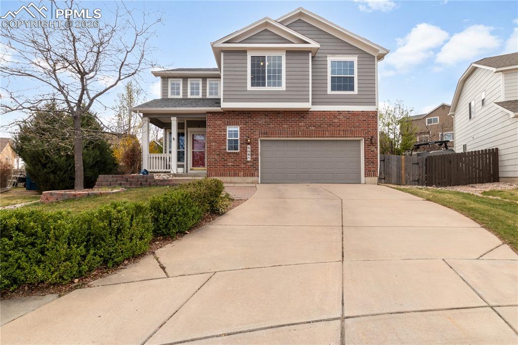 Image 1 of 39: Traditional home with brick siding, a porch, concrete driveway, and an atta