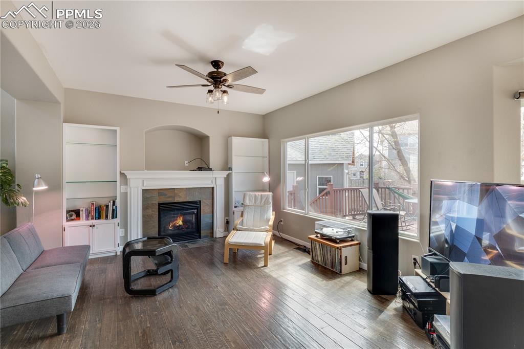 Image 11 of 39: Living room featuring dark wood-style flooring, a ceiling fan, and a tiled 