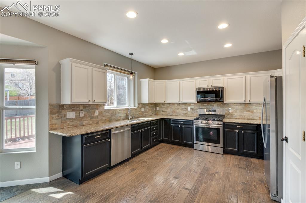 Image 13 of 39: Dual tone kitchen featuring two tone color scheme, light stone counters, st