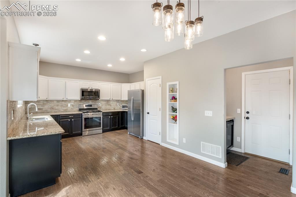 Image 14 of 39: Kitchen with dual tone cabinetry, light stone counters, stainless steel app