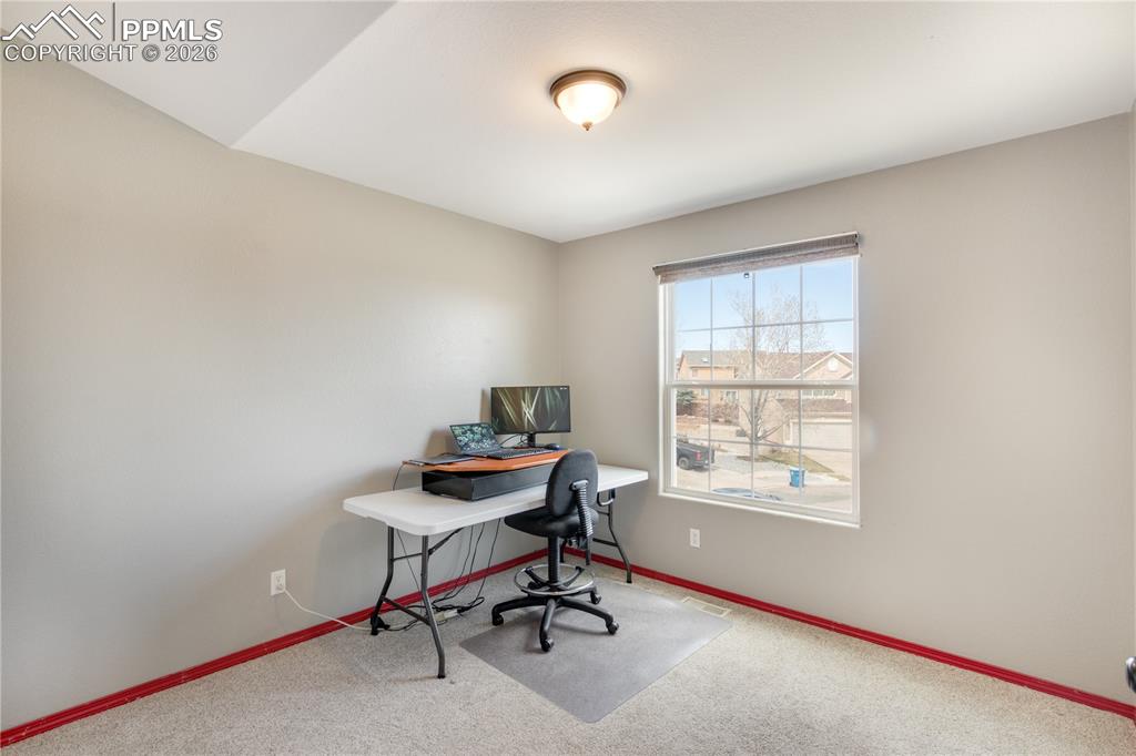 Image 23 of 39: Office area with light colored carpet and baseboards