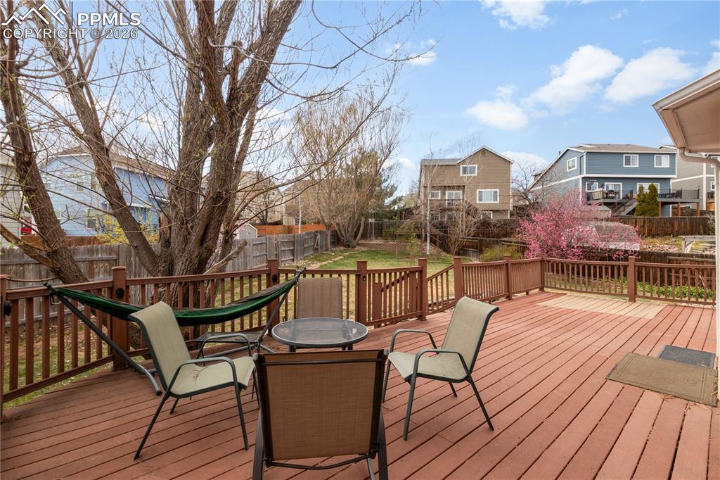 Image 32 of 39: Wooden terrace with a fenced backyard, outdoor dining space, and a resident