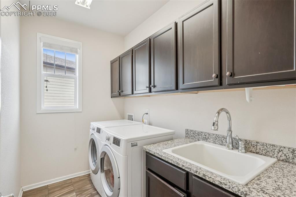 Image 21 of 50: Laundry area featuring washing machine and clothes dryer, cabinets and sink