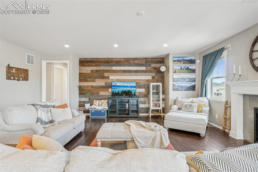 Image 3 of 50: Living room with a fireplace, feature walls, wood flooring, recessed lighti