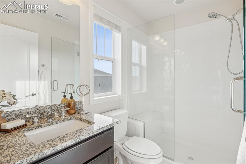 Image 31 of 50: Bathroom with a shower stall, toilet, and vanity