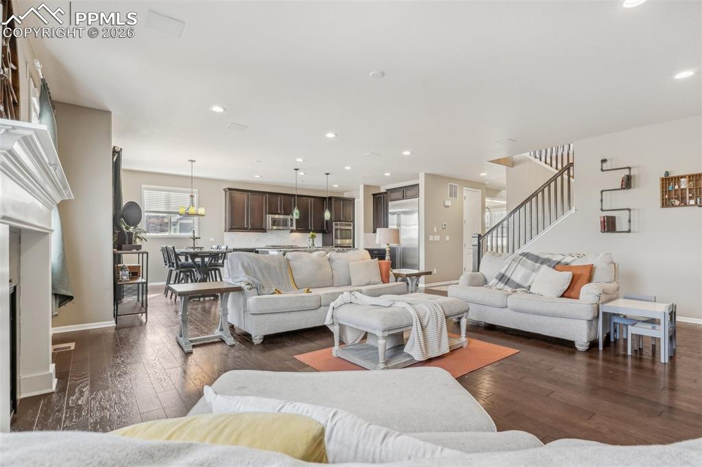 Image 5 of 50: Living area with dark wood flooring, stairs, baseboards, and recessed light