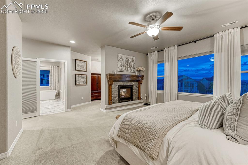 Image 17 of 48: Bedroom with carpet flooring, ensuite bath, recessed lighting, a fireplace,