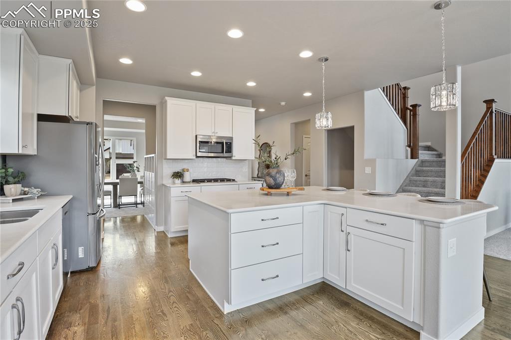 Image 10 of 50: Kitchen with stainless steel appliances, a chandelier, wood finished floors