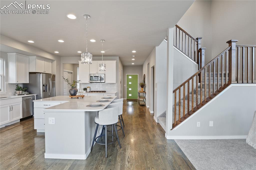 Image 11 of 50: Kitchen featuring stainless steel appliances, white cabinetry, decorative b
